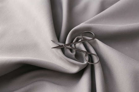 Manicure scissors on a gray silk background. beauty concept