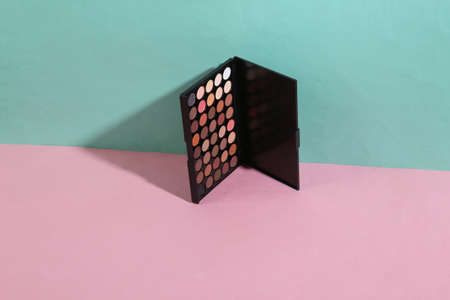 beauty and fashion minimalist scene. Eye shadow palette on a blue pink pastel background with trendy...