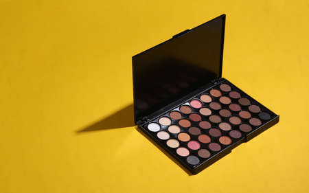 Bright make up eye shadow palette on yellow background. beauty still life.の写真素材
