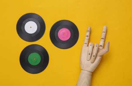 Vinyl records and wooden hand showing Rock gesture on yellow background. top view. Minimalist music concept. rock'n'rollの写真素材