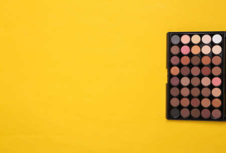 Bright make up eye shadow palette on yellow background. beauty still life. top view. copy spaceの写真素材