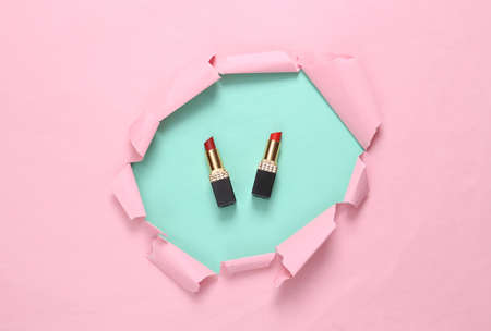 Lipsticks on a pink background with a torn hole. Minimalism beauty still life. creative layoutの写真素材