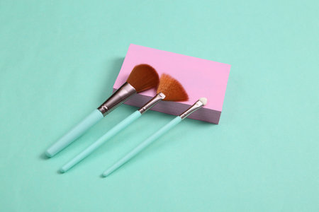 Minimalistic beauty scene. Makeup brushes with pink platform on blue background.