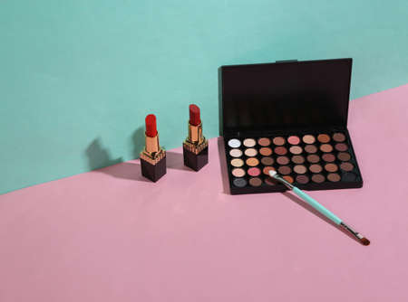 beauty and fashion minimalist scene. Eye shadow palette, lipstick and makeup brush on blue pink pastel background with trendy shadows. creative layoutの写真素材