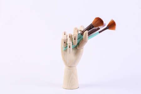 Wooden hand holds make-up brushes on white background. beauty still lifeの写真素材
