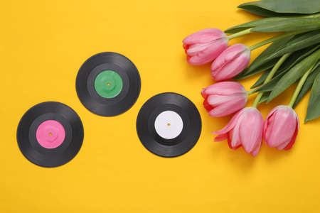 Pink tulips and vinyl records on yellow background. Romantic, music, love concept. flat layの写真素材