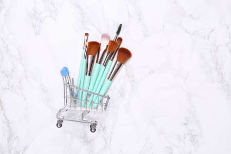 Shopping cart with makeup brushes on marble backgroundの写真素材
