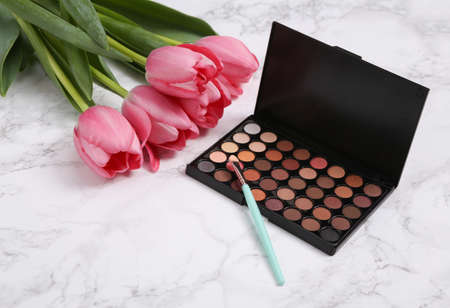 Make-up eye shadow palette with Pink tulips on marble background. Romantic, beauty, love conceptの写真素材