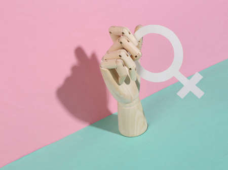 Wooden hand holds venus symbol on pink blue pastel backgroundの写真素材