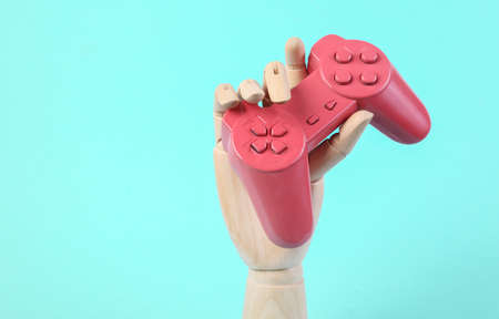 Wooden hand holds pink gamepad on blue background