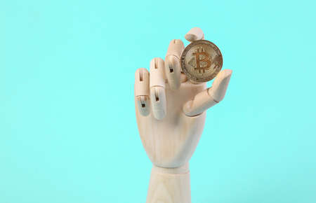Wooden hand holding bitcoin on blue background.の写真素材
