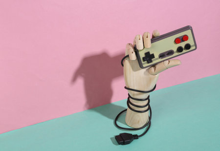 Wooden hand holding retro gamepad on blue pink pastel background. trendy shadow. concept art....