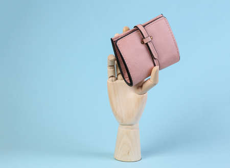 Wooden hand holds leather wallet on blue backgroundの写真素材
