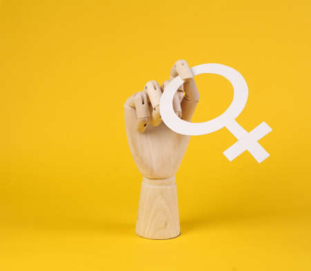 Wooden hand holds venus symbol on yellow backgroundの写真素材