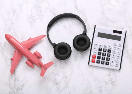 travel concept. Calculator with headphones, plane on marble surface. top viewの写真素材