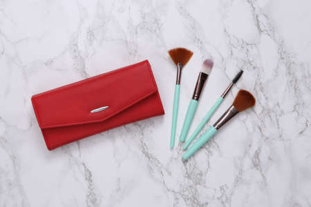 Cosmetic bag and makeup brushes on marble surface