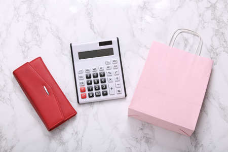 Calculator with shopping bag and wallet on a marble surface. top viewの写真素材