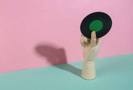 Wooden hand holding vinyl record on blue pink pastel background. trendy shadow. concept art. minimalism. creative layoutの写真素材