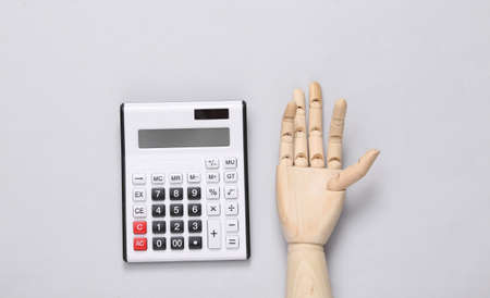 Wooden hand and calculator on gray background. top viewの写真素材