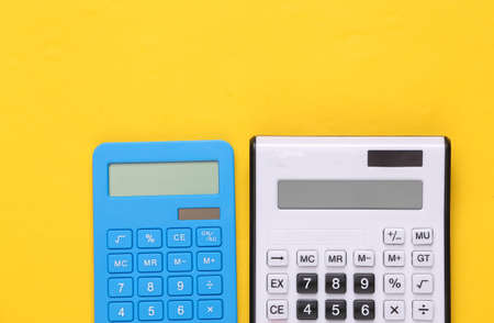 Two calculators on a yellow background. top view
