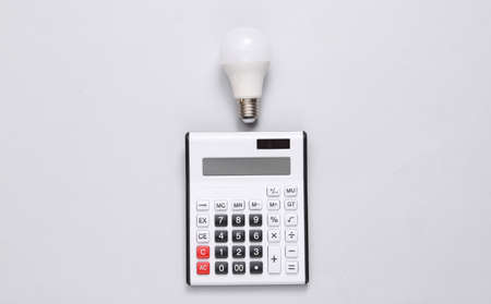 Calculator and led light bulb on gray background. top view. flat lay
