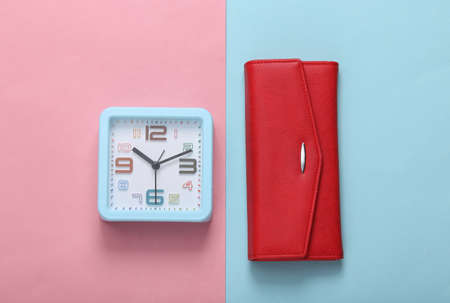 Square alarm clock with wallet on pink blue background. top view. flat lay