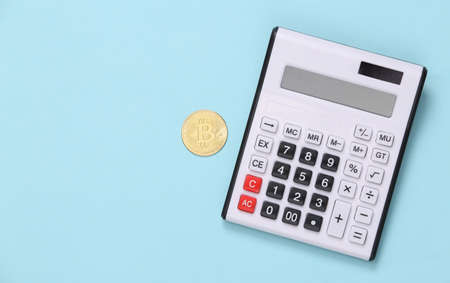 Calculator and bitcoin on blue background. top viewの写真素材