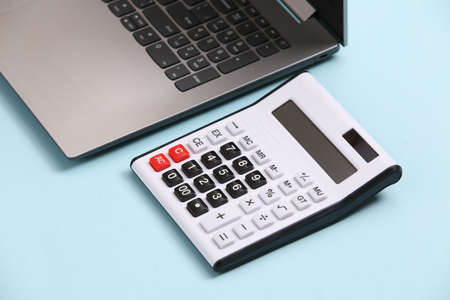 Calculator and laptop on blue background.
