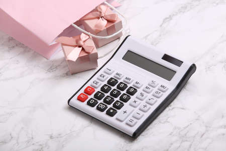 Calculator and shopping bag with gift boxes on a marble surface.の写真素材