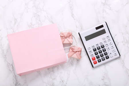Calculator and shopping bag with gift boxes on a marble surface.の写真素材