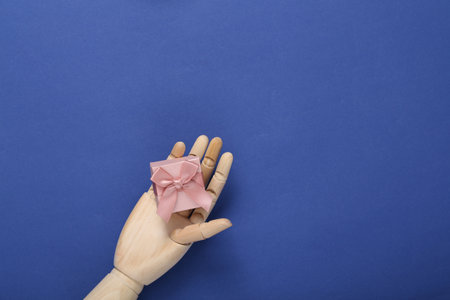 Wooden hand holding gift box on blue backgroundの写真素材