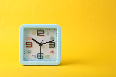 Square alarm clock on yellow backgroundの写真素材