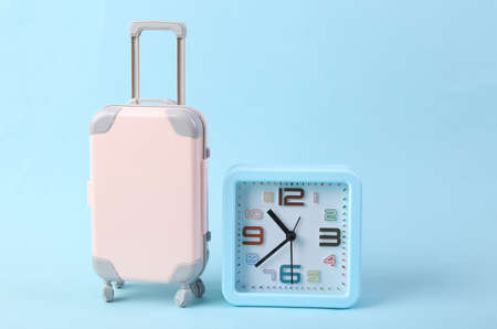 Travel time. Alarm clock and mini luggage model on blue backgroundの写真素材