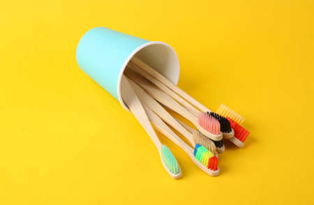 Lots of bamboo eco toothbrushes in cup on yellow backgroundの写真素材