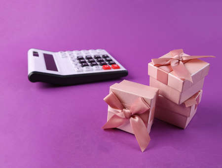 Stack of gift boxes and calculator on purple backgroundの写真素材