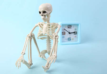 Skeleton and alarm clock on a blue background. dead lineの写真素材