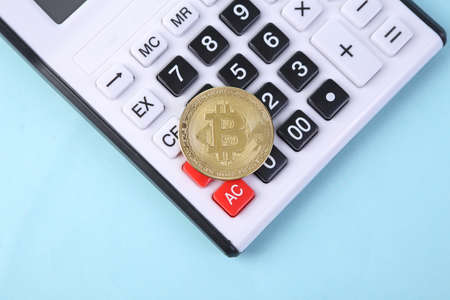 Calculator and bitcoin on blue background