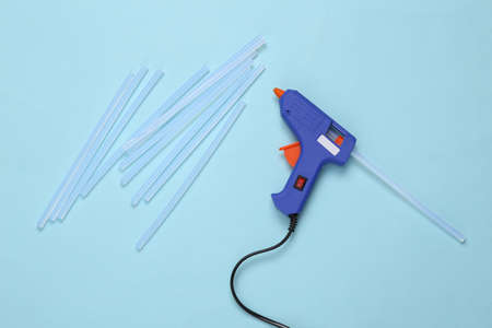 Glue gun with glue stick on blue background.の写真素材