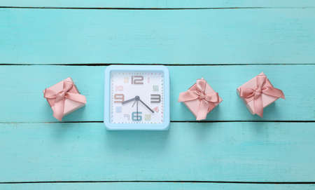 Gift boxes and alarm clock on a blue wooden background.の写真素材