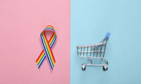 LGBT rainbow ribbon pride tape symbol and shopping trolley on pink blue pastel background.の写真素材