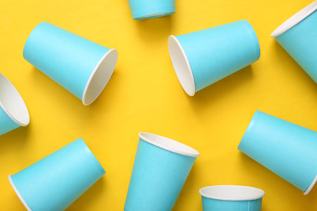 Empty blue cardboard coffee cups on yellow background. minimalismの写真素材