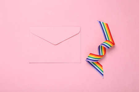 Envelope with LGBT rainbow ribbon pride tape symbol on pink background. Valentine's day, love conceptの写真素材