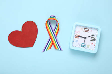 LGBT rainbow ribbon pride tape symbol and alarm clock, heart on blue background. top view