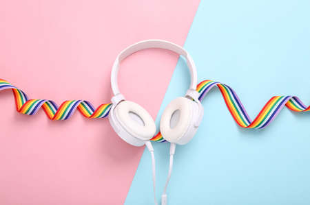 Stereo headphones with LGBT rainbow ribbon tape on blue pink background. top viewの写真素材