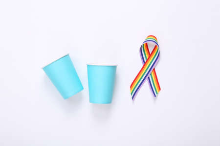 Paper cups with LGBT rainbow ribbon pride tape symbol on white background. top view