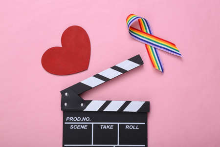 Clapperboard and LGBT rainbow ribbon pride tape symbol with heart on pink background. love movieの写真素材