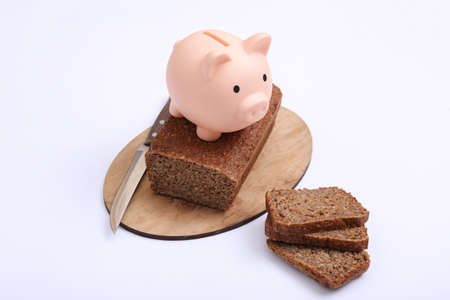 Piggy bank with Sliced whole grain rye bread on white background. economy concept