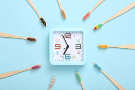 Eco toothbrushes with alarm clock on blue background. Dental care concept. top viewの写真素材