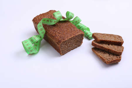 Measuring tape and diet whole grain rye bread on a white background. weight loss, diet concept
