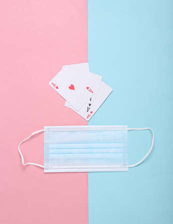 Medical mask and four aces on a pink blue background